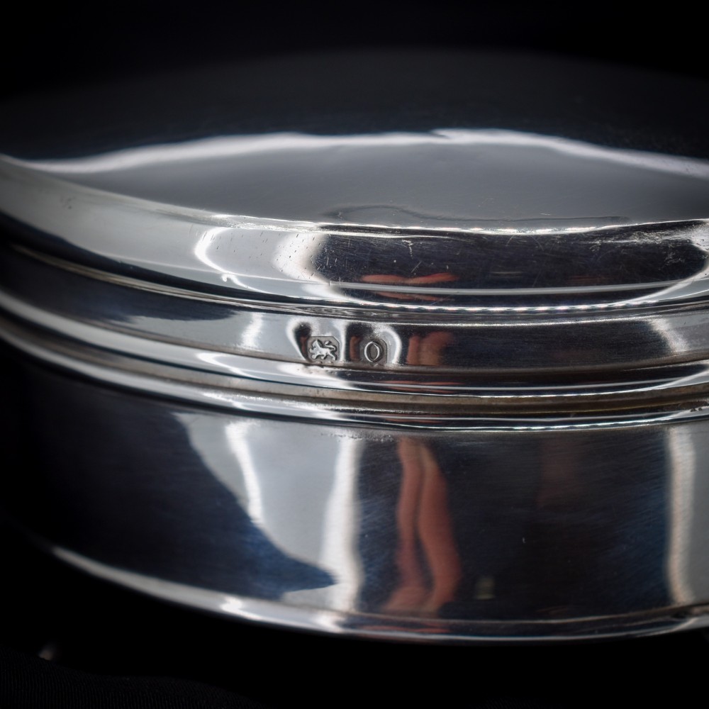 An oval sterling silver trinket box with a smooth polished hinged lid supported on four small cabriole feet. View II