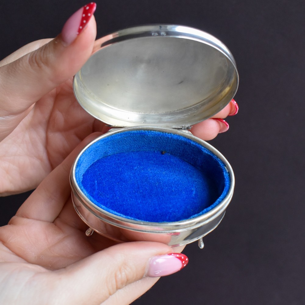 An oval sterling silver trinket box with a smooth polished hinged lid supported on four small cabriole feet. View VII