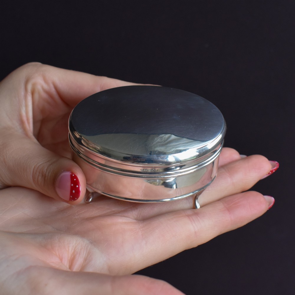 An oval sterling silver trinket box with a smooth polished hinged lid supported on four small cabriole feet. View VIII