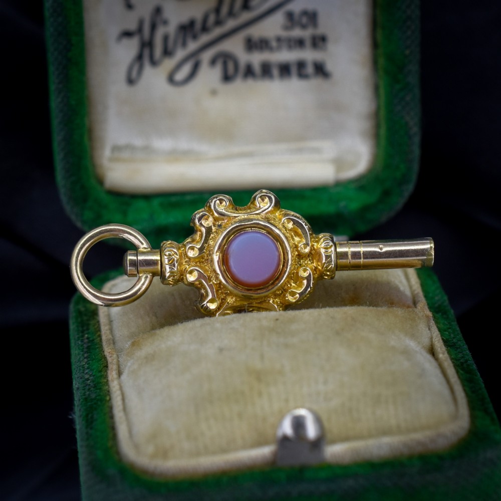 An antique gold watch key pendant featuring scrollwork ornamentation around a central dark green bloodstone seal, topped with a suspension ring. View II