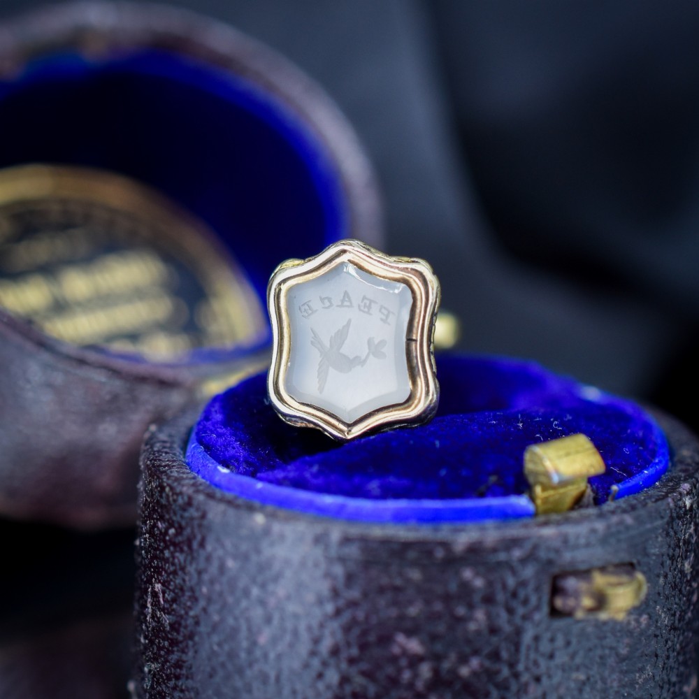 An antique gold fob seal featuring a carved chalcedony intaglio displaying a dove of peace carrying an olive branch above a reversed inscription.