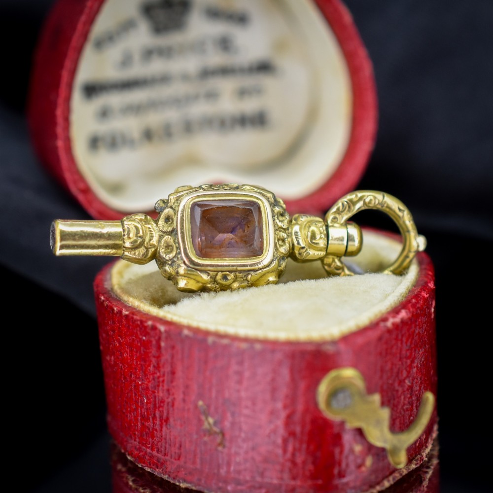 An antique gold-cased pocket watch key pendant inset with a square red agate stone and decorated with intricate chased patterns. View III