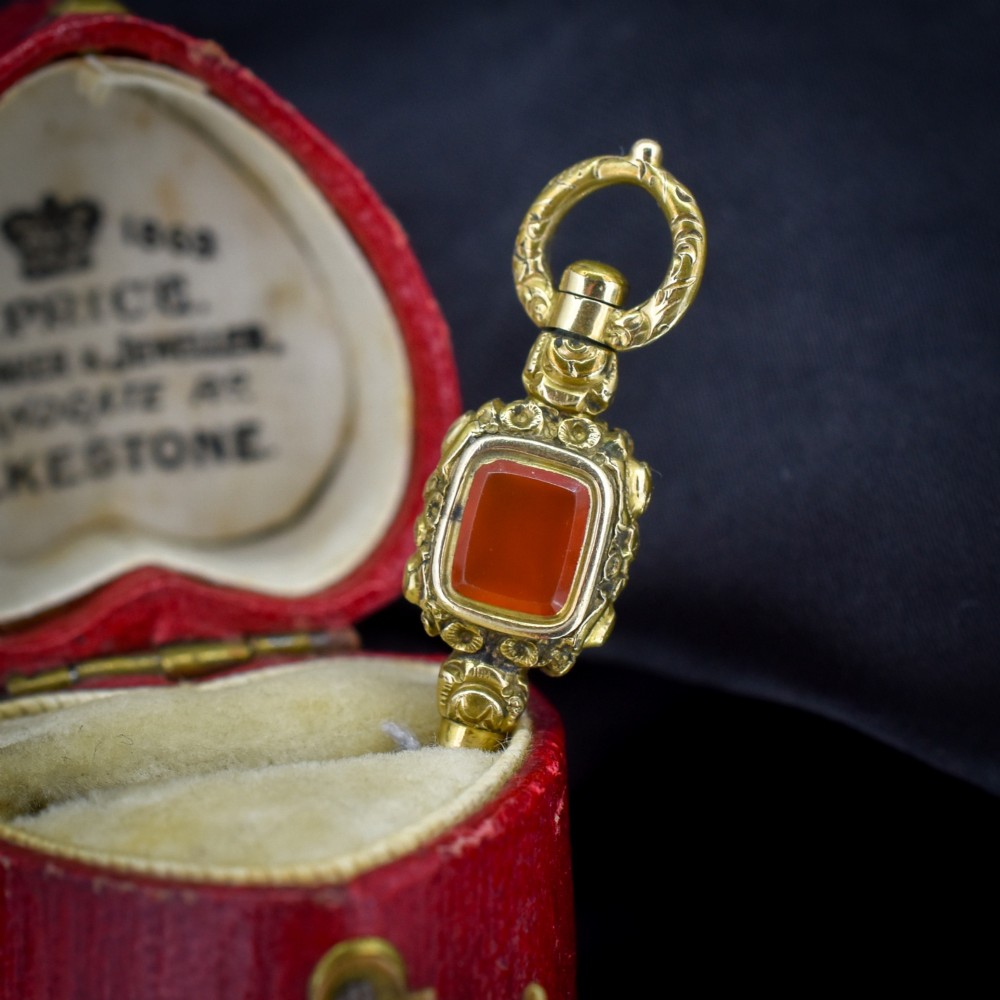 An antique gold-cased pocket watch key pendant inset with a square red agate stone and decorated with intricate chased patterns. View IV