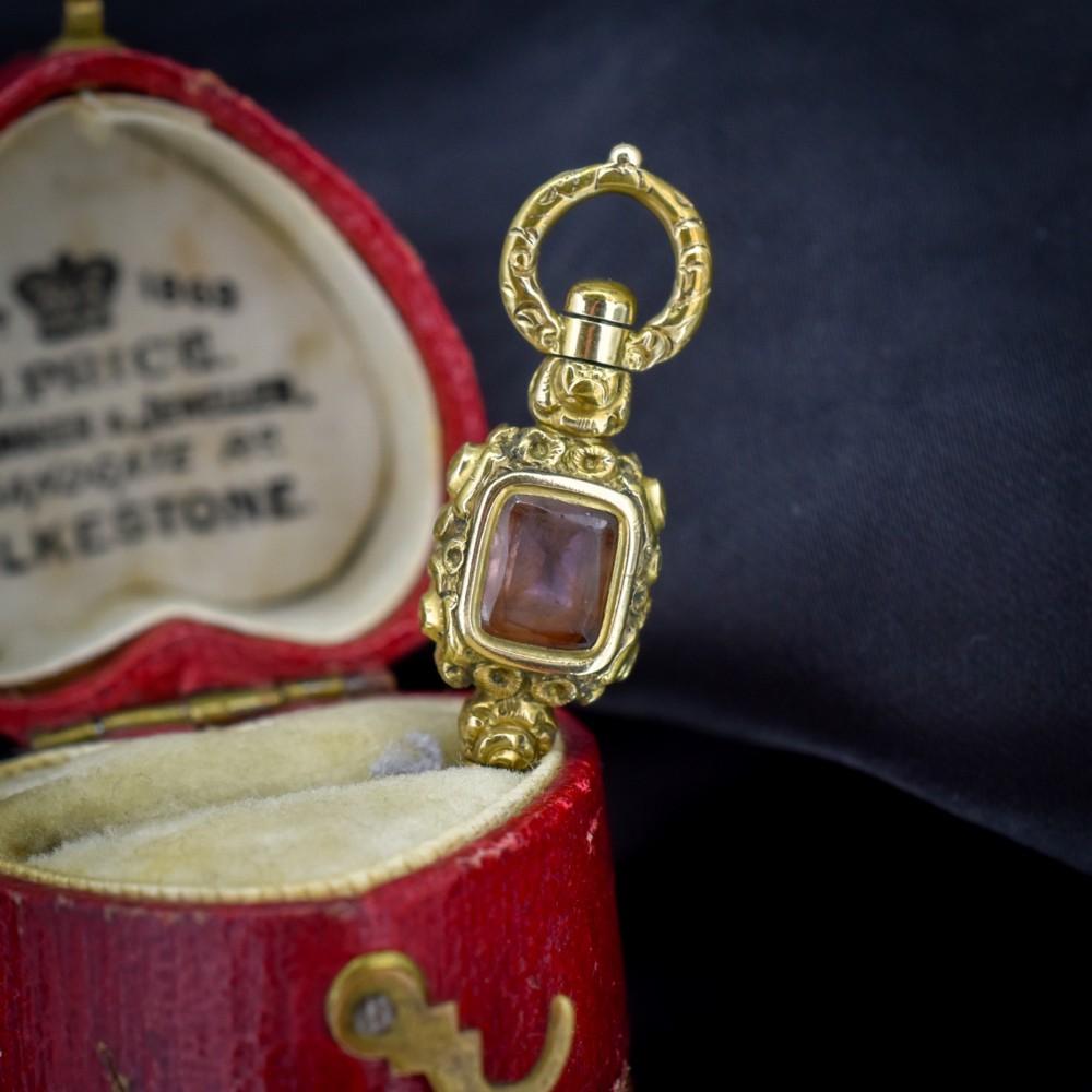 An antique gold-cased pocket watch key pendant inset with a square red agate stone and decorated with intricate chased patterns. View V
