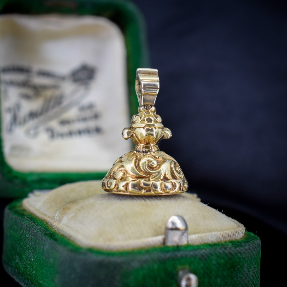 An oval orange-red carnelian gem carved with an intaglio mother bird motif, set within a chased gold-cased fob mount. View IV