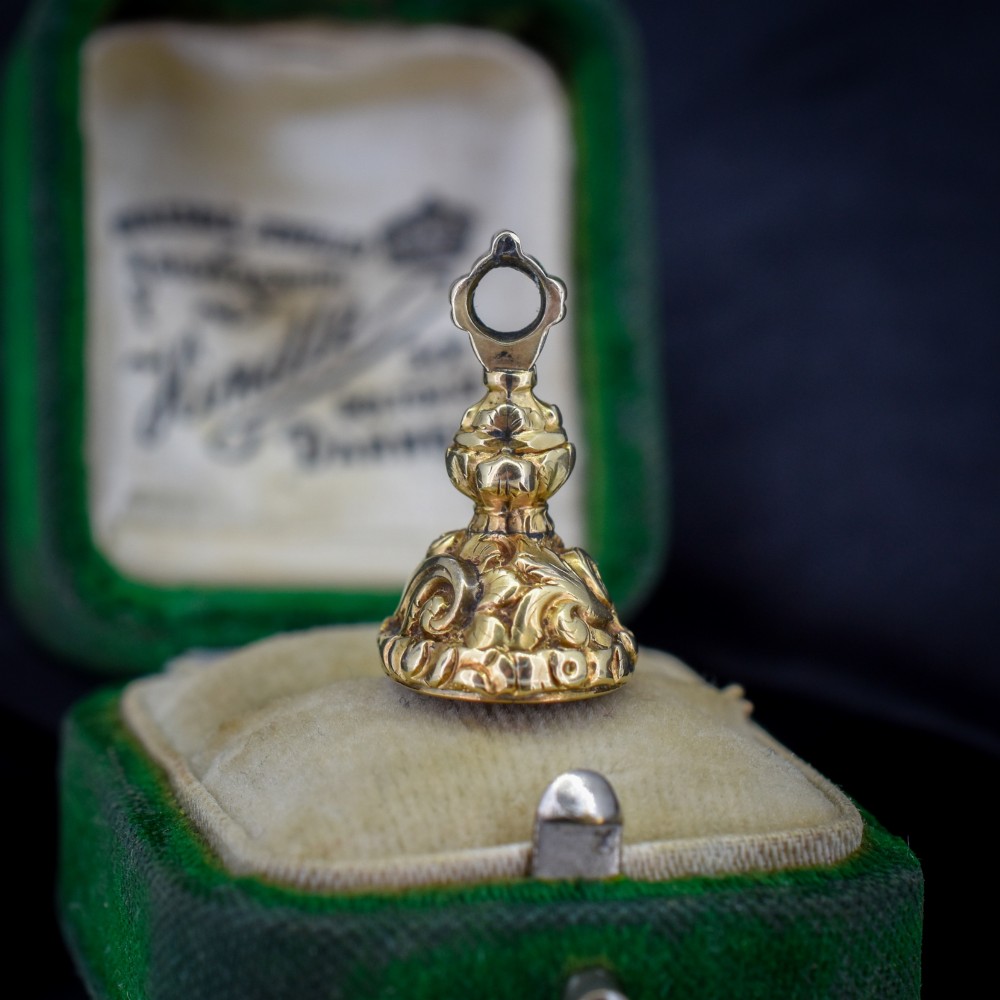 An oval orange-red carnelian gem carved with an intaglio mother bird motif, set within a chased gold-cased fob mount. View V