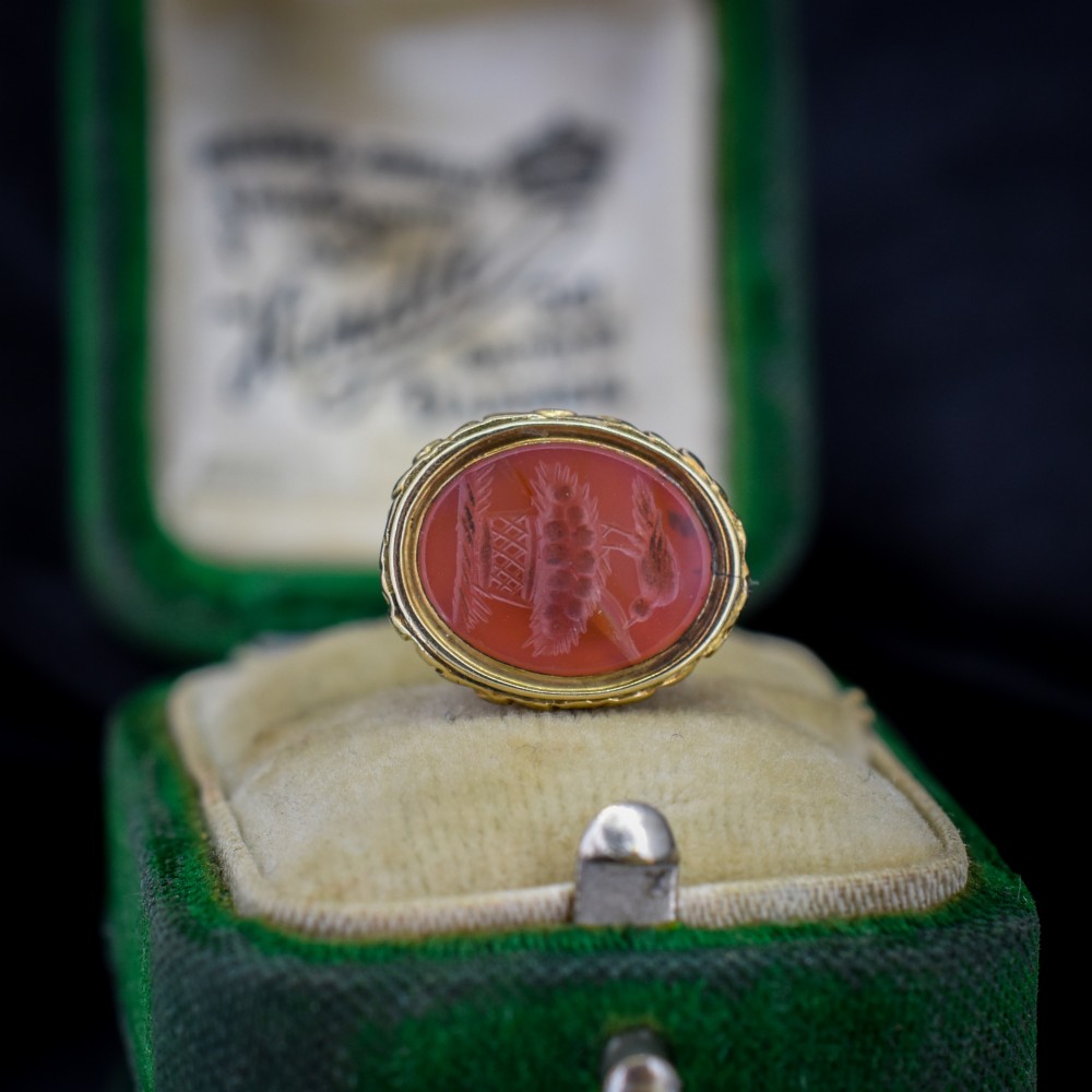 An oval orange-red carnelian gem carved with an intaglio mother bird motif, set within a chased gold-cased fob mount. View VI