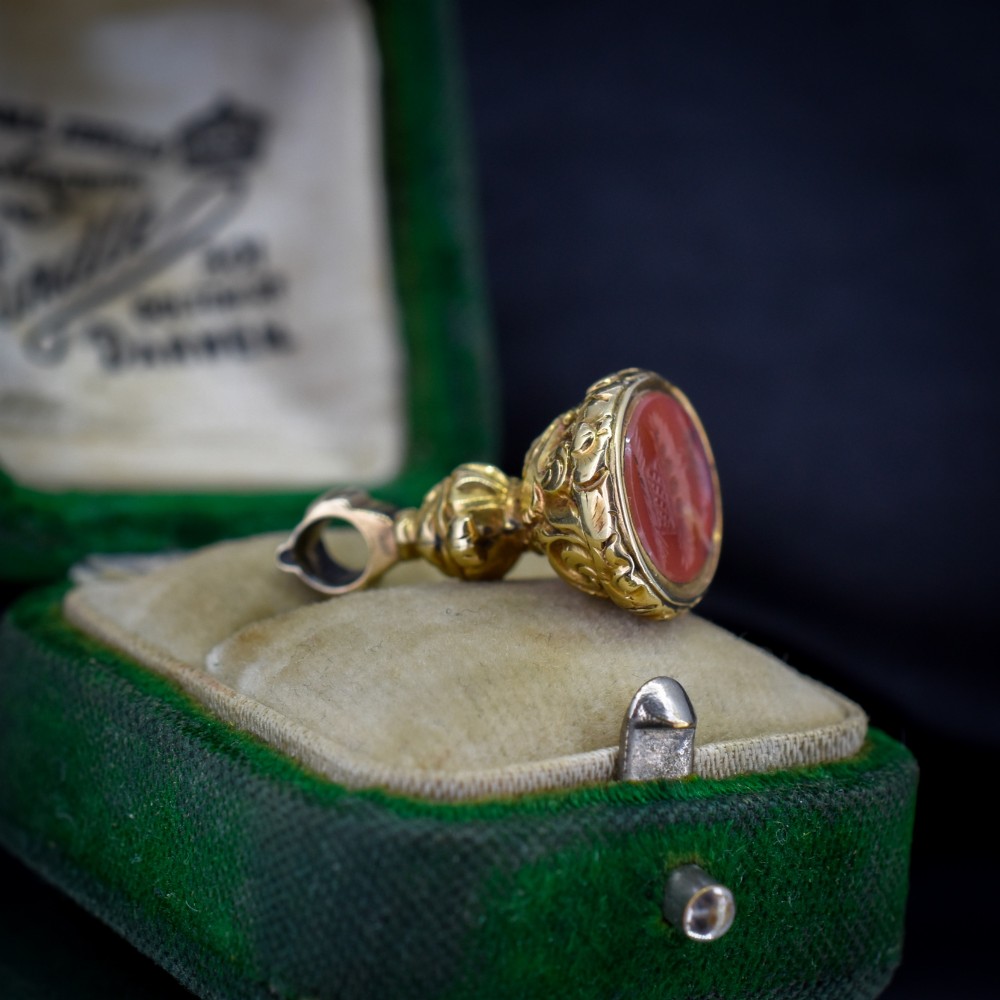 An oval orange-red carnelian gem carved with an intaglio mother bird motif, set within a chased gold-cased fob mount. View VII