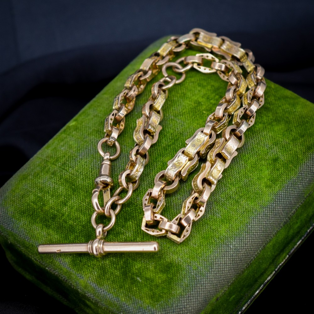 An antique 9ct yellow gold Albert watch chain with star engraved fancy links, a central T-bar, and a swivel dog clip fastener.