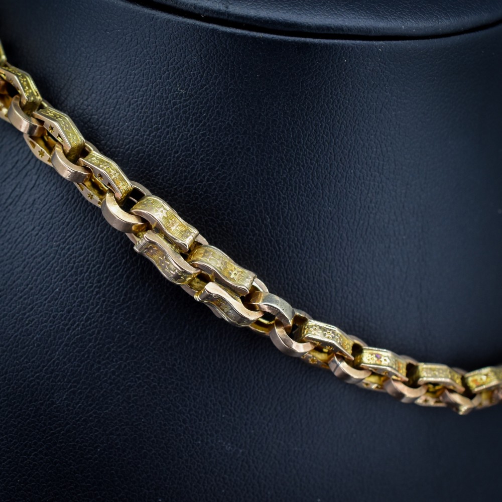 An antique 9ct yellow gold Albert watch chain with star engraved fancy links, a central T-bar, and a swivel dog clip fastener. View V