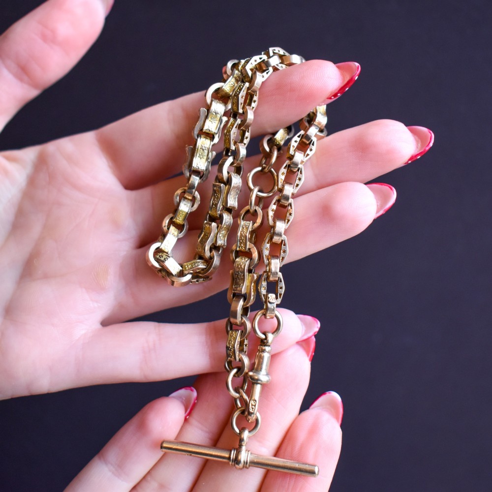 An antique 9ct yellow gold Albert watch chain with star engraved fancy links, a central T-bar, and a swivel dog clip fastener. View X