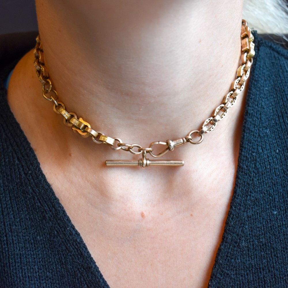 An antique 9ct yellow gold Albert watch chain with star engraved fancy links, a central T-bar, and a swivel dog clip fastener. View XI