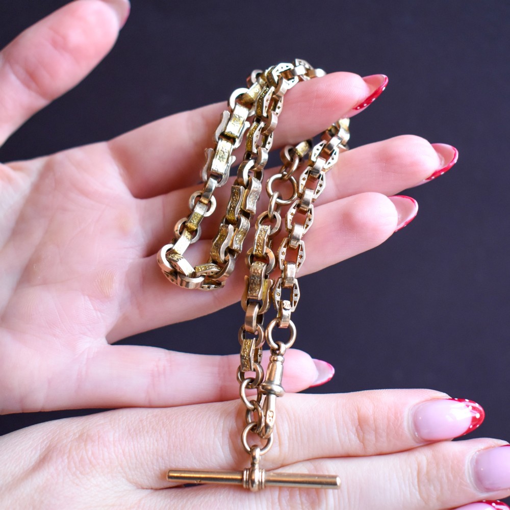 An antique 9ct yellow gold Albert watch chain with star engraved fancy links, a central T-bar, and a swivel dog clip fastener. View XII