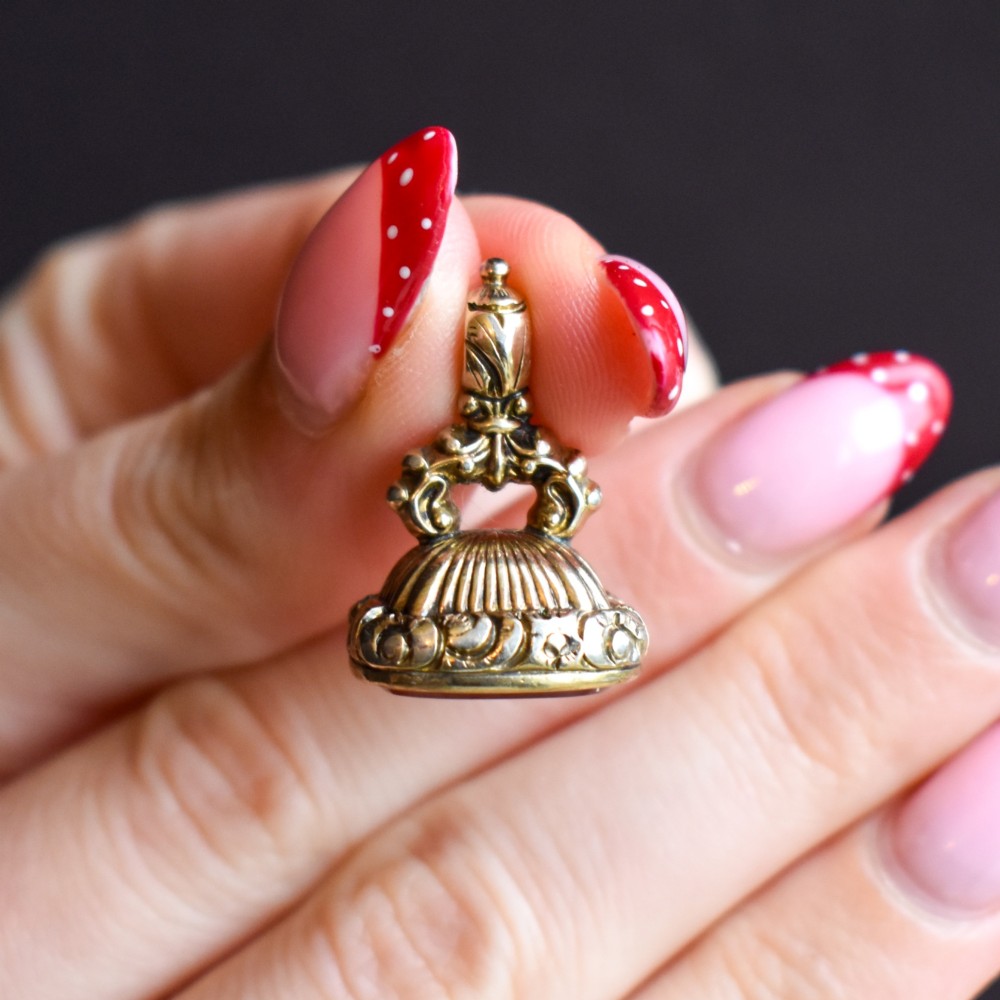 A Georgian gold fob seal set with a red carnelian intaglio engraved with a sailing ship and the French inscription Telle Est La Vie. View X