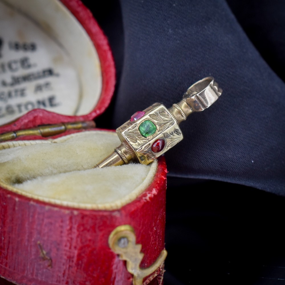 An antique yellow gold barrel watch key fob pendant with engraved scrollwork and a vertical setting of acrostic gemstones. View V
