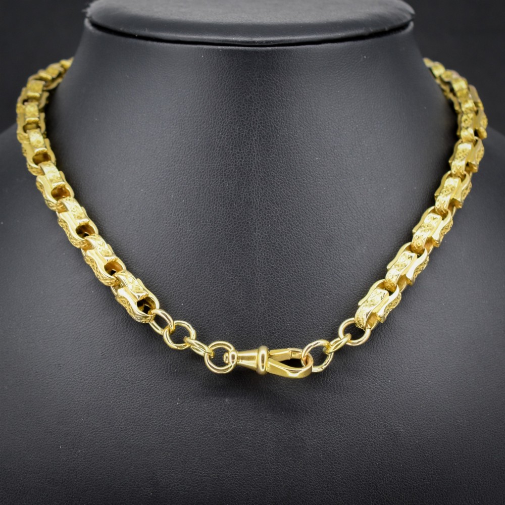 An antique 10ct yellow gold tulip link chain necklace featuring textured engraved links and a swivel dog clip clasp.