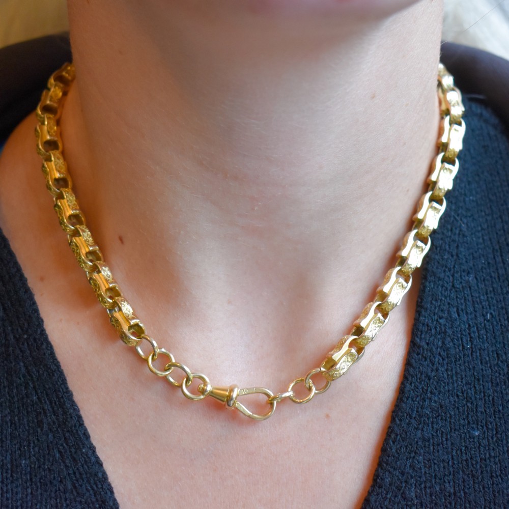 An antique 10ct yellow gold tulip link chain necklace featuring textured engraved links and a swivel dog clip clasp. View IX