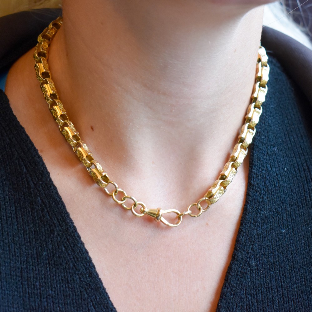 An antique 10ct yellow gold tulip link chain necklace featuring textured engraved links and a swivel dog clip clasp. View X