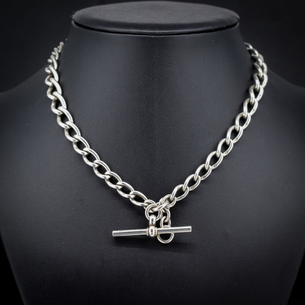 An Edwardian sterling silver Albert watch chain featuring heavy oval links, a central T-bar, and a dog clip clasp. View II