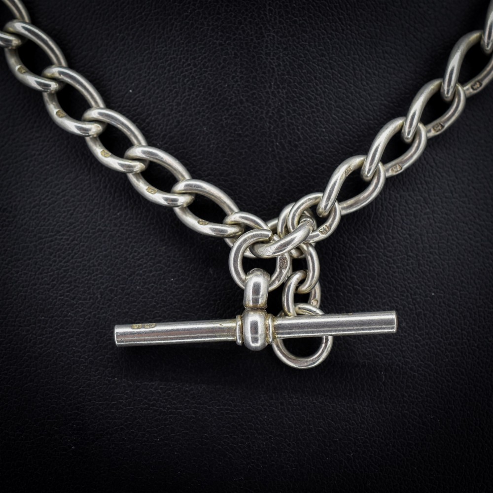 An Edwardian sterling silver Albert watch chain featuring heavy oval links, a central T-bar, and a dog clip clasp. View III
