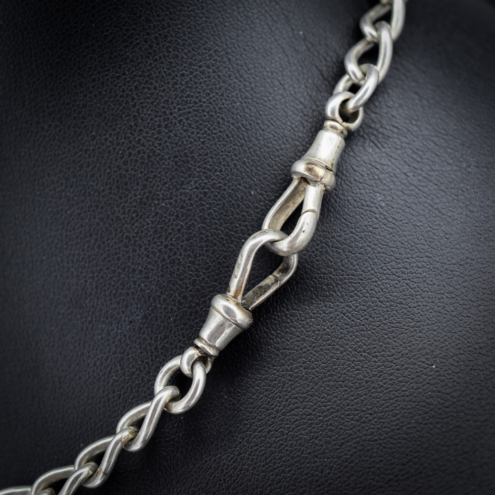 An Edwardian sterling silver Albert watch chain featuring heavy oval links, a central T-bar, and a dog clip clasp. View V