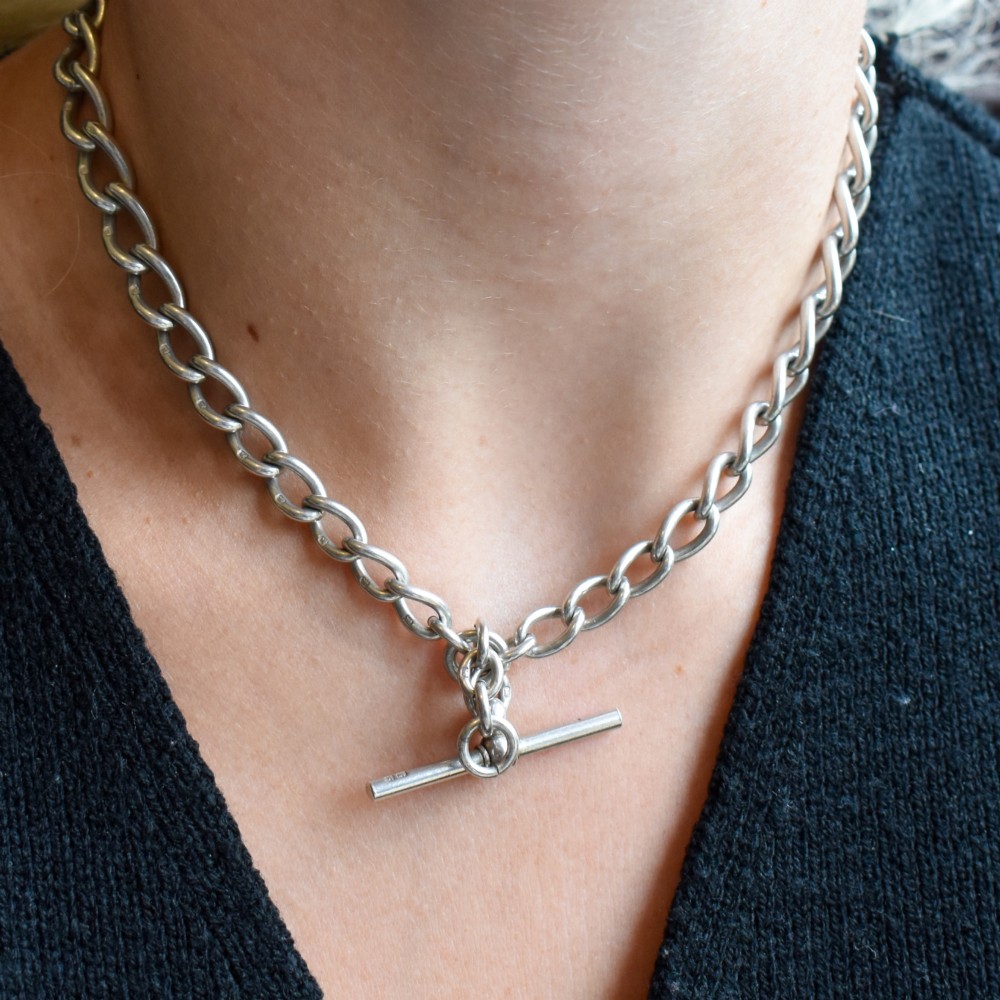 An Edwardian sterling silver Albert watch chain featuring heavy oval links, a central T-bar, and a dog clip clasp. View XI