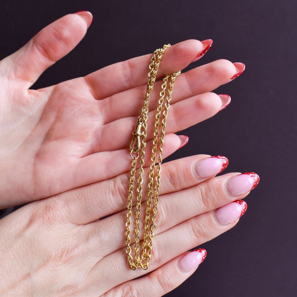 An antique yellow gold twenty-inch chain necklace featuring love knot links and a functional swivel dog clip fastener. View VIII