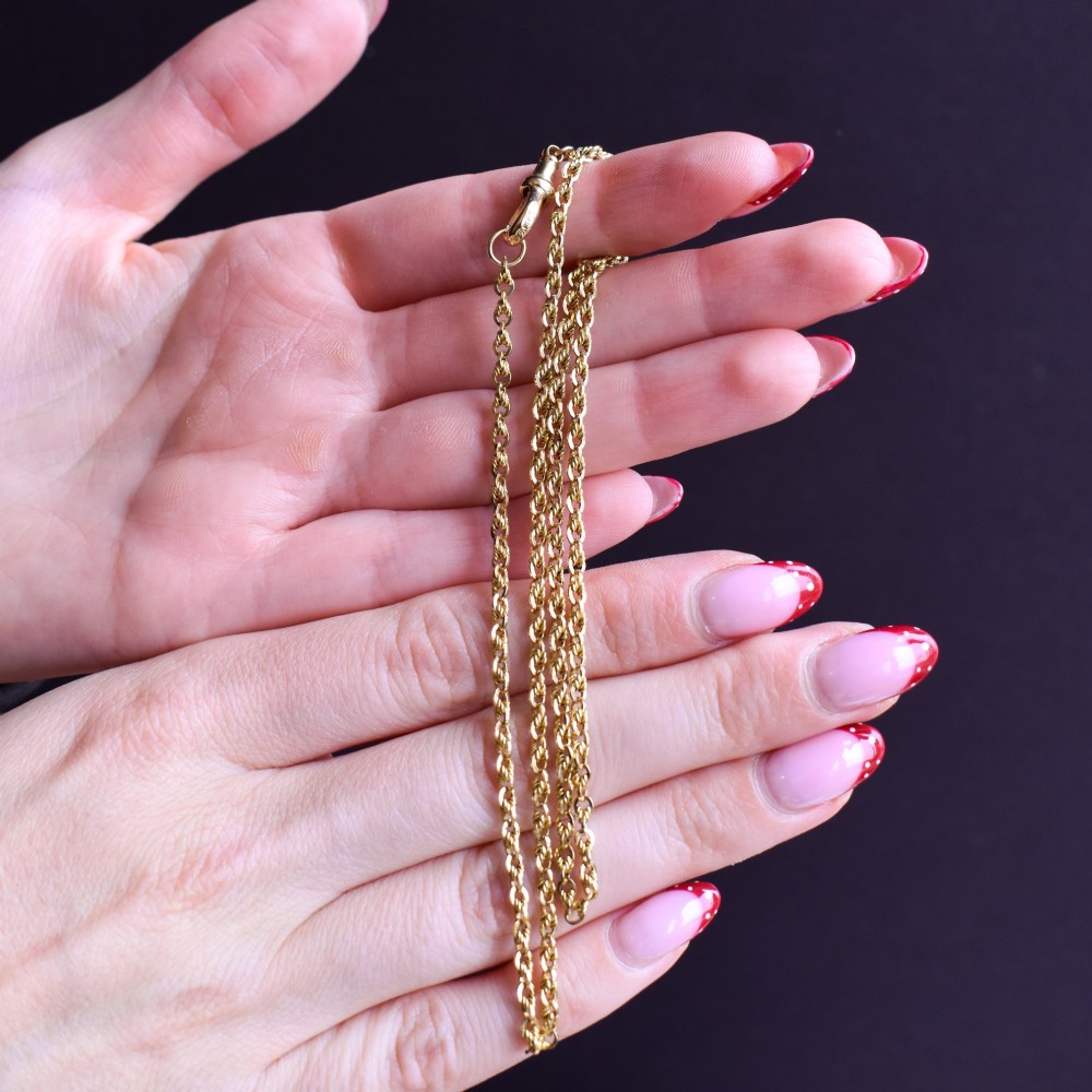 An antique yellow gold twenty-inch chain necklace featuring love knot links and a functional swivel dog clip fastener. View IX