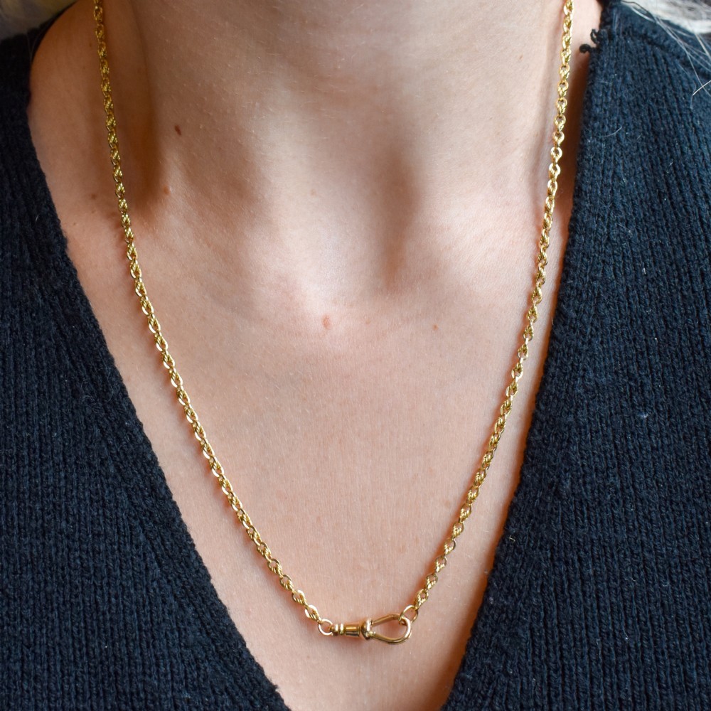 An antique yellow gold twenty-inch chain necklace featuring love knot links and a functional swivel dog clip fastener. View X