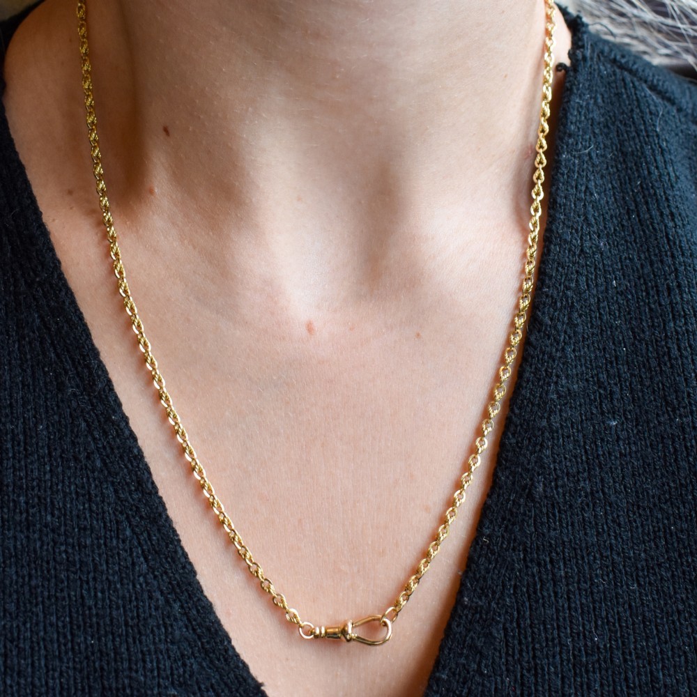 An antique yellow gold twenty-inch chain necklace featuring love knot links and a functional swivel dog clip fastener. View XI