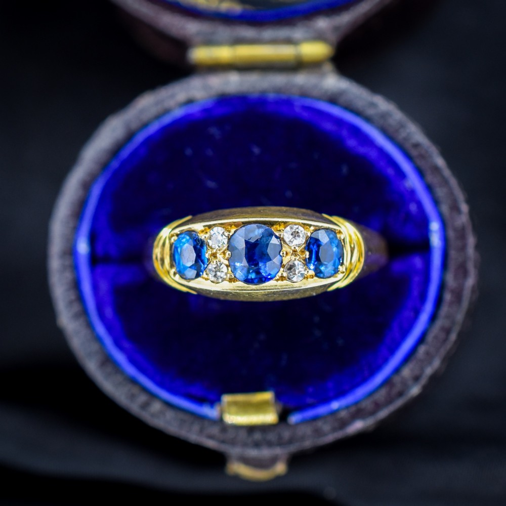 An Edwardian 18ct yellow gold boat ring set with three blue sapphires and accent diamonds in a carved setting. View II