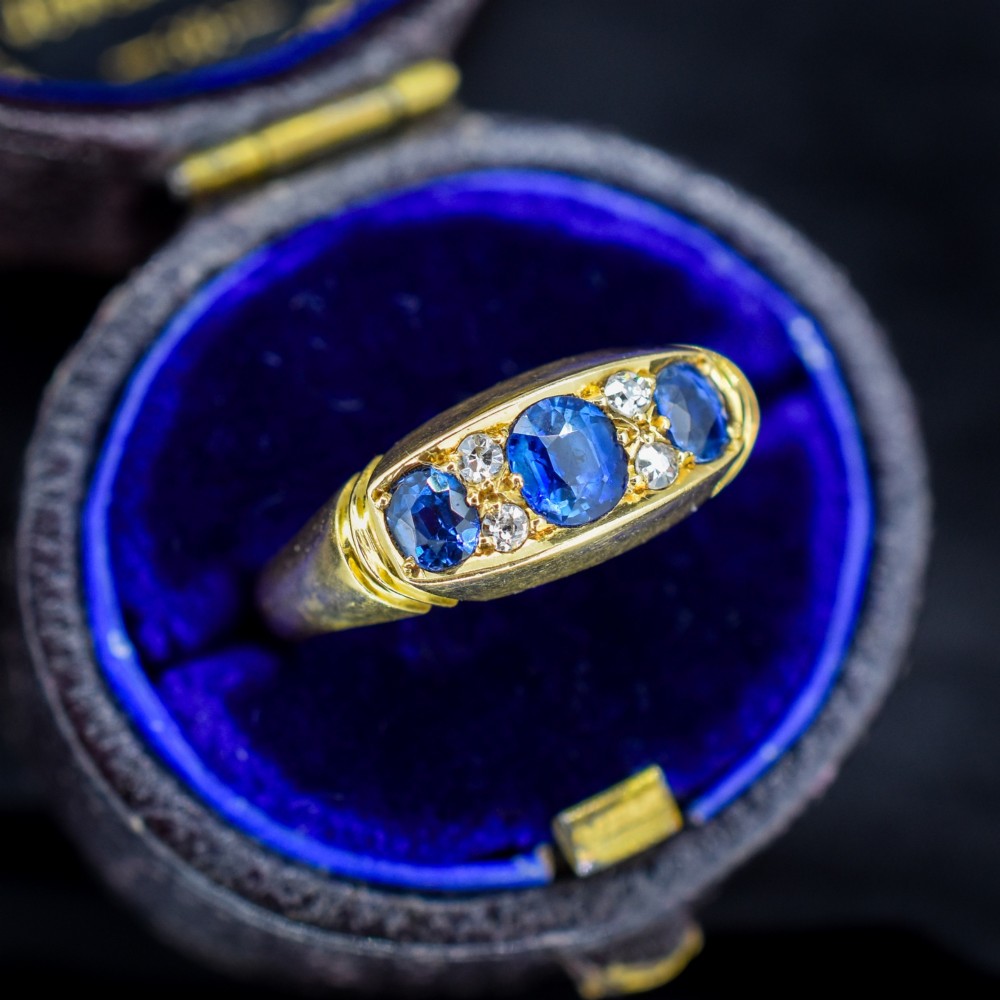 An Edwardian 18ct yellow gold boat ring set with three blue sapphires and accent diamonds in a carved setting. View III