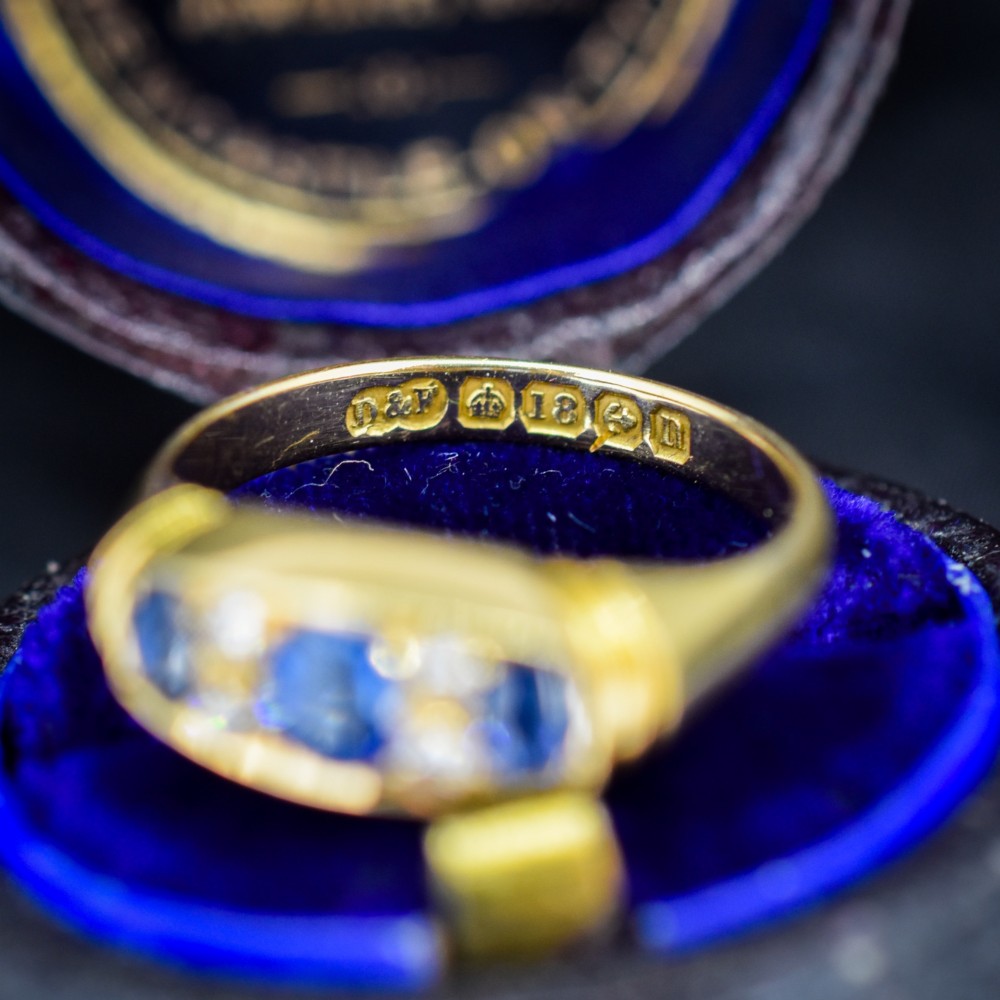 An Edwardian 18ct yellow gold boat ring set with three blue sapphires and accent diamonds in a carved setting. View IV