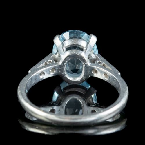 fig 1. An oval-cut light blue aquamarine gemstone set in a four-claw mount with channel-set diamond shoulders on a silver-coloured metal band.