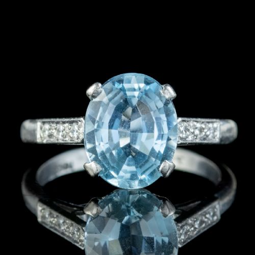 fig 2. An oval-cut light blue aquamarine gemstone set in a four-claw mount with channel-set diamond shoulders on a silver-coloured metal band.
