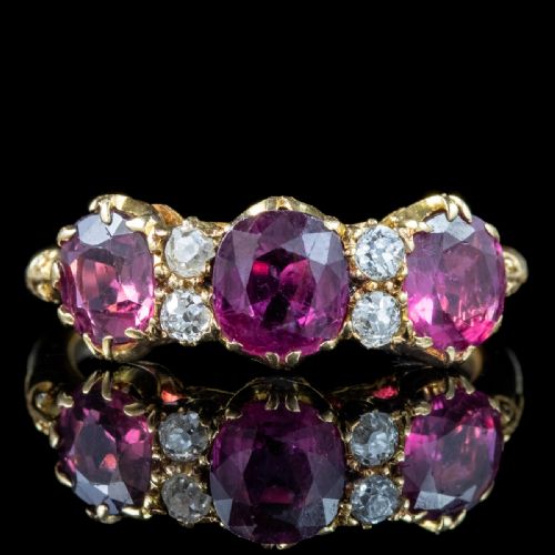 fig 5. A Victorian yellow gold ring featuring three oval red rubies separated by pairs of small round white diamonds set in a carved scroll mount.