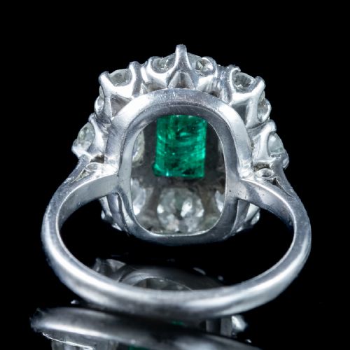 fig 3. An antique Edwardian cluster ring featuring a central rectangular step-cut green emerald framed by eight old-cut diamonds in a white metal setting.