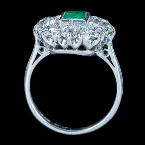 fig 4. An antique Edwardian cluster ring featuring a central rectangular step-cut green emerald framed by eight old-cut diamonds in a white metal setting.