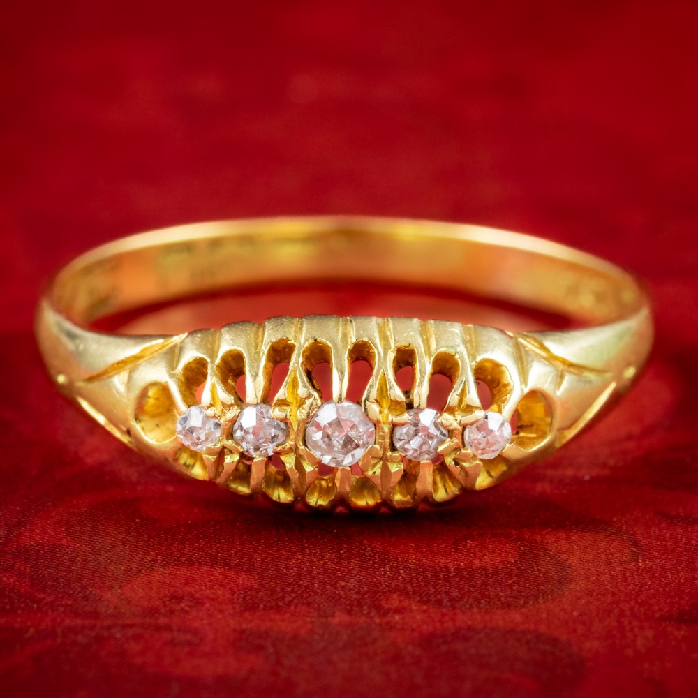 An Edwardian yellow gold band featuring a carved openwork gallery set with five graduated round diamonds.