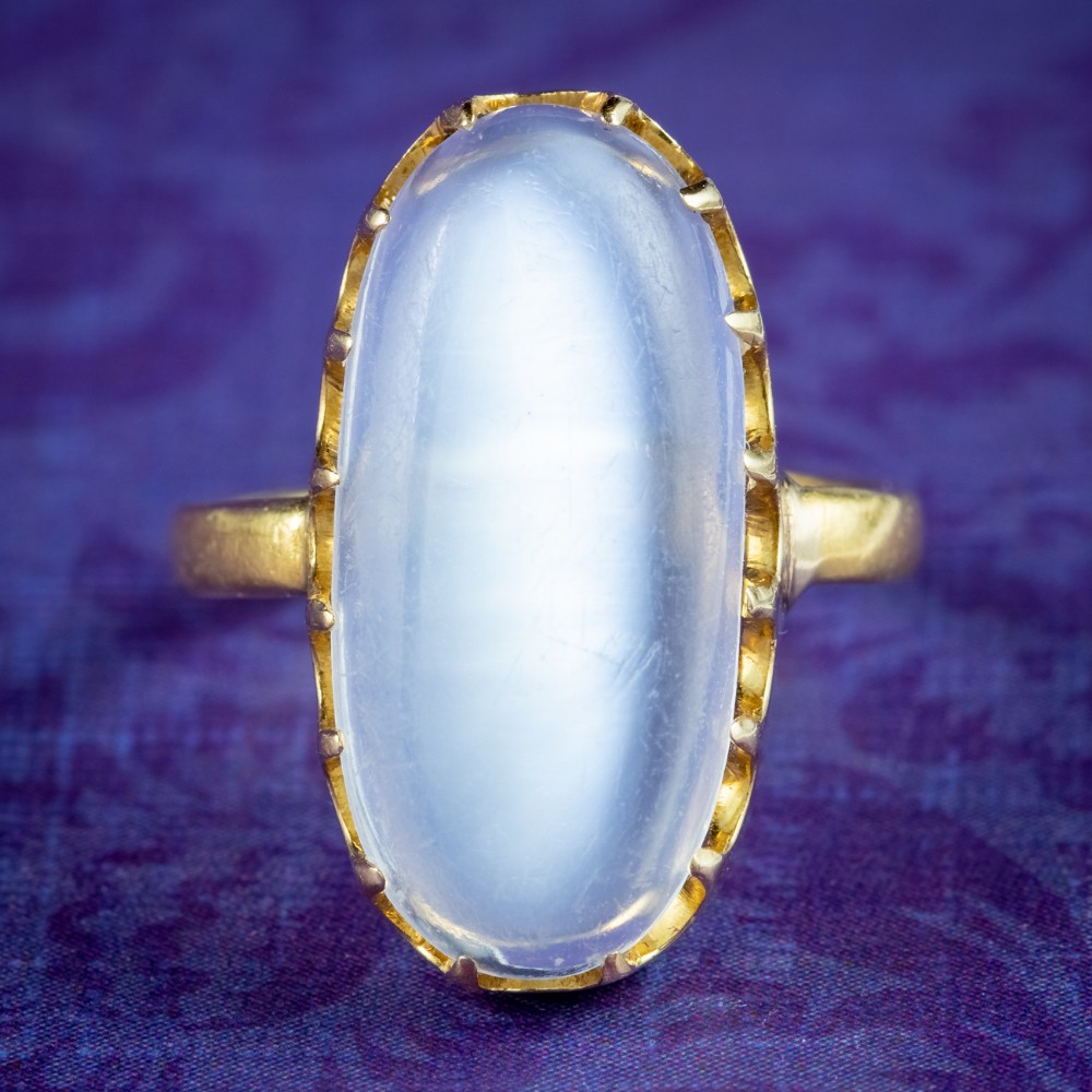 An antique Victorian ring featuring a large oval cabochon moonstone set in a multi-claw yellow gold mounting.