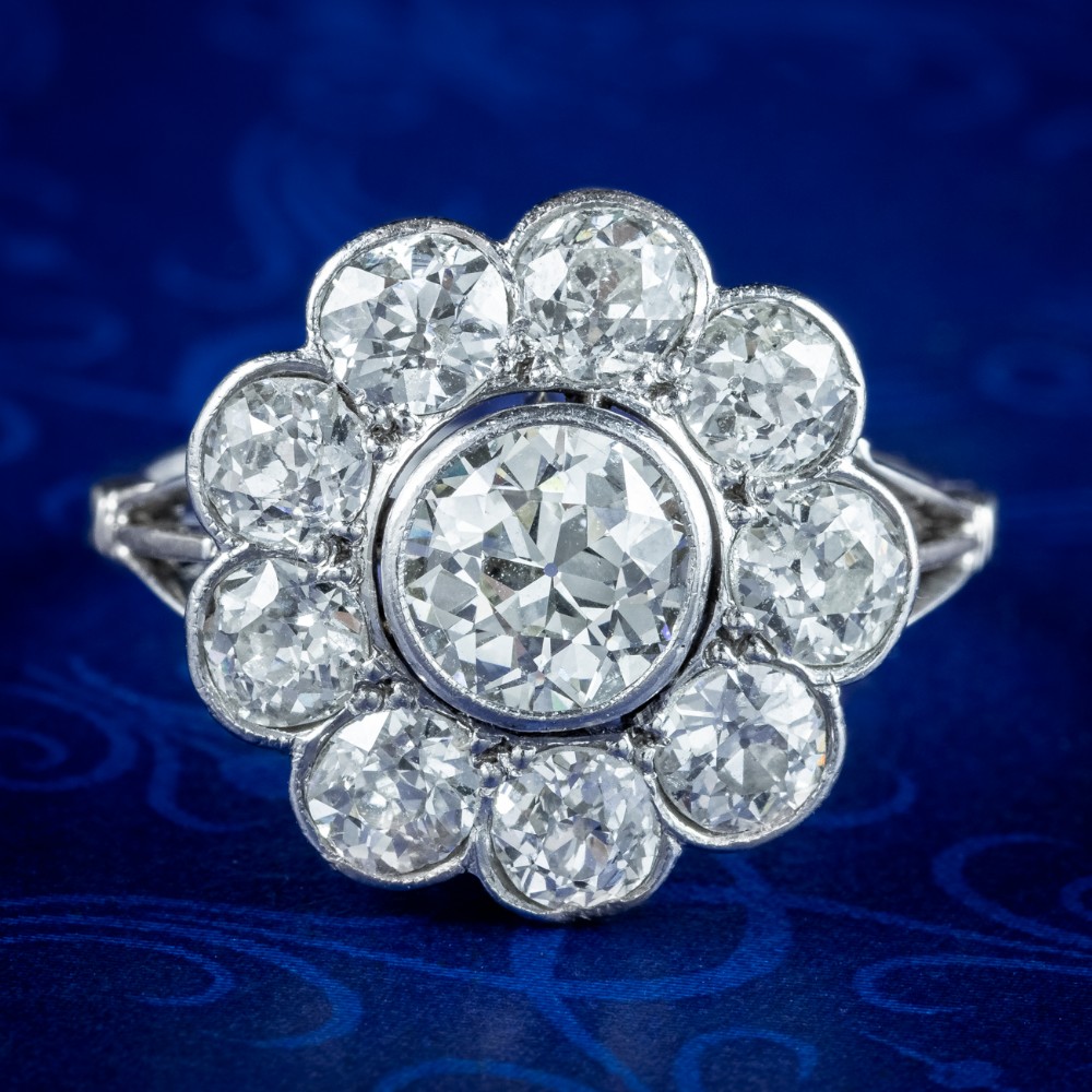 An Edwardian platinum ring featuring a large old European cut central diamond surrounded by nine round diamonds forming a daisy cluster.