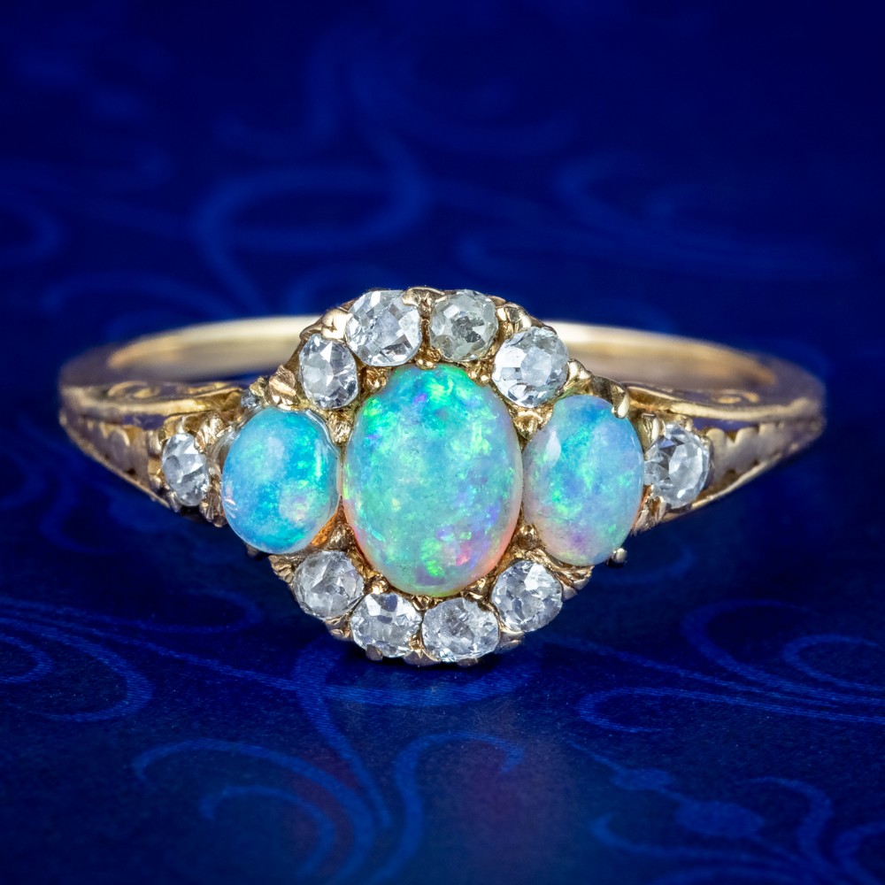 A Victorian yellow gold ring set with three oval cabochon opals surrounded by small diamonds.