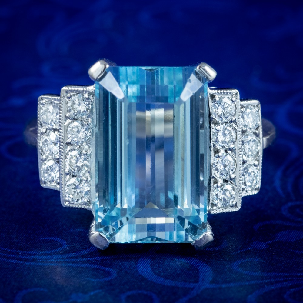 A vintage 1950s cocktail ring featuring a large emerald-cut blue aquamarine flanked by stepped shoulders set with round diamonds.