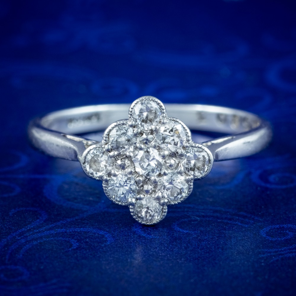 An Edwardian diamond cluster ring featuring old cut diamonds set in a milgrain-bordered quatrefoil pattern in platinum.