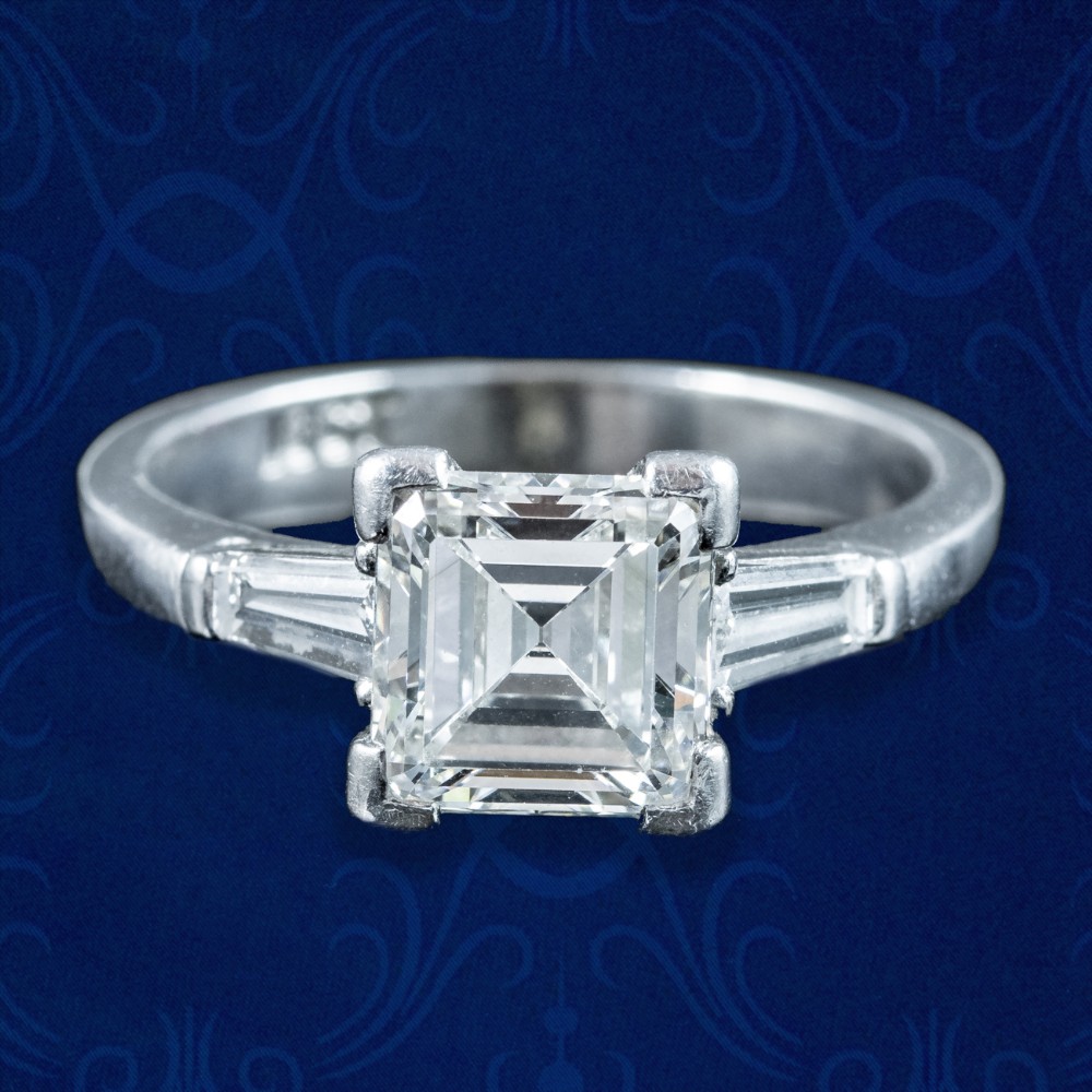 An Art Deco platinum ring featuring a central square step-cut diamond flanked by two tapered baguette diamonds.