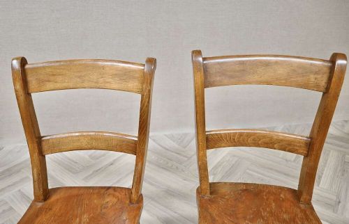 A pair of antique warm brown wooden barback kitchen chairs featuring solid contoured seats, double horizontal back rails, and turned legs. View V