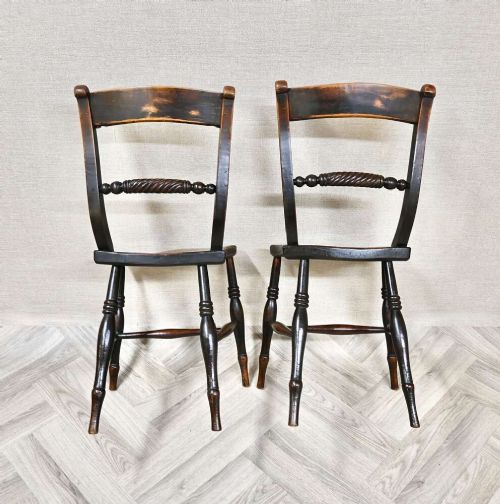 A pair of Victorian wooden kitchen chairs featuring curved top rails, carved rope-twist middle bars, shaped saddle seats, and turned legs. View IV