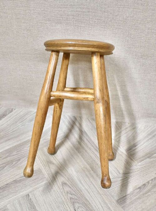 A nineteenth-century round wooden stool featuring four splayed turned legs supported by round stretchers. View II
