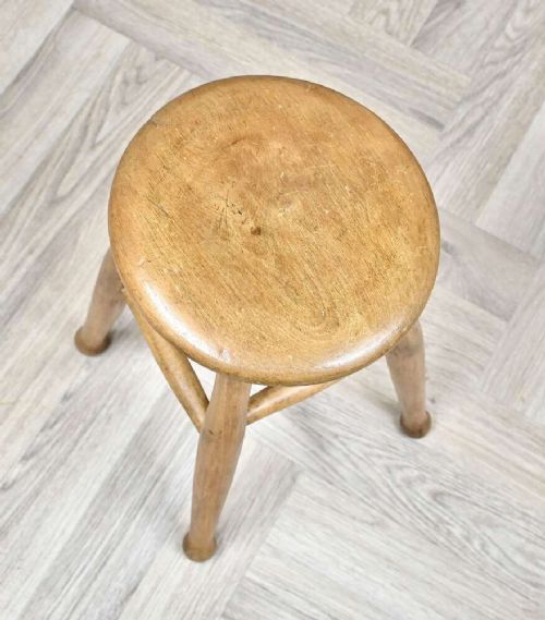 A nineteenth-century round wooden stool featuring four splayed turned legs supported by round stretchers. View III