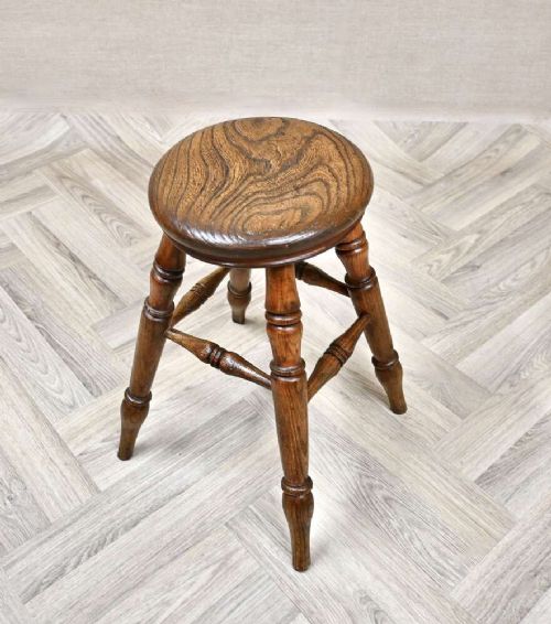 A nineteenth-century turned wooden Windsor stool featuring a circular polished seat supported by four splayed turned legs and turned stretchers. View II